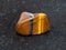 tumbled tiger eye gemstone on dark background