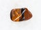 tumbled tiger eye gemstone on white marble