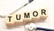 tumor word written on wooden blocks and stethoscope on light white background