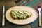 Tuna fish toast with mayonnaise and avocado served on a wooden plate with a coloured napkin on a wooden background