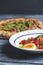 Tuna salad with vegetables, boiled eggs, cherry tomatoes and spices. Pizza with salmon fish, cheese and fresh arugula