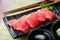Tuna sushi on black plate along with Japanese sauce and green leaf decoration, Japanese food, close up at sushi