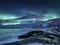 Tungeneset rocks and Aurora Borealis light. Stars trails and northern light. Reflections on the water surface. Senja islands, Norw