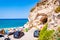 Tunnel cave in the massive rock leading to small cozy closed beach. Tyrrhenian sea coast in Tropea. Parking area and sea promenade