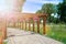 Tunnel of wooden pillars and pots of flowers, gazebo in the park. Sun beam lights