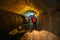 Tunnel worker examines pipeline in underground tunnel