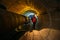 Tunnel worker examines pipeline in underground tunnel