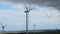 Turbine blades spinning on large wind farm, stormy sky, renewable energy source