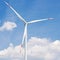 Turbine generator close up against the blue sky with clouds, big blades on the turbine