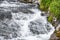 Turbulent spring stream of mountain river. Water foams, breaks into splashes on stones