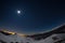 Turin city lights, night view from snow covered Alps by moonlight. Moon and Orion constellation, clear sky, fisheye lens. Italy.