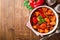 Turkey stew with bell peppers, green beans and tomatoes in bowl on dark wooden table