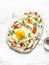 Turkish breakfast - flatbread with fried egg, yogurt, chili sauce and cheese on light background