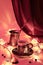 Turkish coffee pot and traditional cup with oriental sweets. Ornate copper metal garland and tea lights. Vivid red and