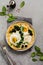 Turkish eggs flatbread with yoghurt, cheese, olives, spinach and red pepper on ceramic vintage plate on gray old background.
