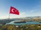 Turkish flag fluttering above picturesque Green Lake Manavgat. Lush green mountainous landscape with clear blue waer