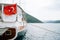 Turkish flag on a yacht sailing on calm water against the backdrop of mountains.