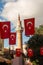 Turkish national flag hang on a rope in the street with a minaret behind