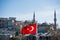 Turkish national flag hang on a rope in the street with a minaret behind