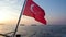Turkish national red flag with moon and star waving in wind against sunset