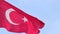 Turkish national state flag waving in the wind on a flagpole against the blue sky close up