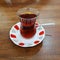 Turkish tea in a transparent small glass with a painted saucer. Wooden table
