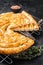 Turkish Tepsi Boregi, Round Borek cheese pie on kitchen board. Black background. Top view