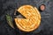 Turkish Tepsi Boregi, Round Borek cheese pie on kitchen board. Black background. Top view