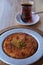 Turkish traditional delight Kunefe in plate and a glass of black tea.