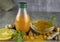 Turmeric juice in a bottle, lemon, orange and turmeric powder on a wooden background