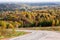 Turn of the road, leaving in the autumn Russian forest with colorful yellow, red and green trees a sunny day