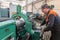 Turner worker manages the metalworking process of mechanical cutting on a lathe