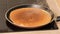 Turning a pancake in a pan. Big round pancake on induction frying pan.