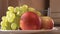 Turning plate with fruit on white background, apear, grapes, peaches, apple