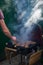 Turning pork barbecue covered by thick smoke