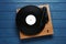 Turntable with vinyl record on blue wooden background, top view