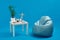 Turquoise bean bag, white coffee table with green flower in pot, candles, succulent, wooden figurine of human, glasses