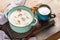 Turquoise ceramic pan with mushroom cream soup, cup with sour cream and crackers on old wooden board on wooden rustic background