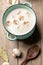 Turquoise ceramic pan with mushroom cream soup, fresh champignons, spoon, garlic and bay leafs on wooden background