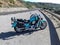 Turquoise classic motorcycle parked on the edge of a coastal road