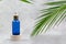 Turquoise cosmetic bottle with dropper on beige podium with palm leaves. Natural beauty organic moisturizing oil. Skin Care