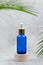 Turquoise cosmetic bottle with dropper on beige podium with palm leaves. Skin Care Cosmetics