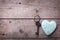 Turquoise decorative heart and vintage key on aged wooden backg