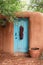 Turquoise door with chile ristra in adobe wall in Santa Fe, New Mexico