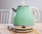 Turquoise electric tea kettle on wooden table