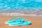 Turquoise flip flops abandoned on sandy seashore