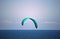 TURQUOISE KITE SURFER SAIL OVER THE SEA AGAINST THE SKY OFF THE COAST AT UMHLANGA ROCKS, KWA-ZULU NATAL, SOUTH AFRICA