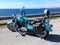 Turquoise motorcycle parked by the sea with Capo Caccia on the background