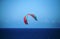 TURQUOISE AND RED KITE SURFER SAIL OVER THE SEA AGAINST THE SKY OFF THE COAST AT UMHLANGA ROCKS, KWA-ZULU NATAL, SOUTH AFRICA