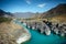 Turquoise river in deep rocky gorge surrounded by high mountains under blue sky on sunny autumn day. Amazing natural landscapes